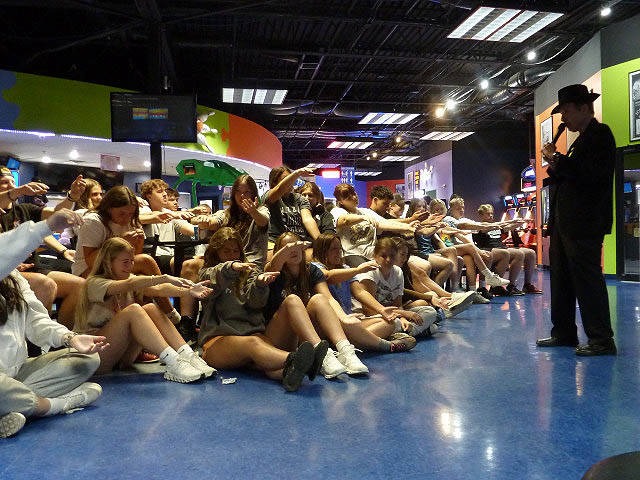 Students stretch their arms out during a hypnosis demonstration at a Chicago area graduation party.