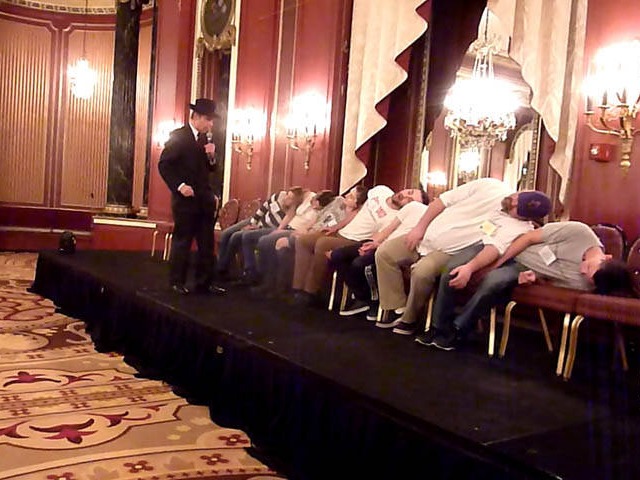 Row of seated volunteers slumped over on each other at a Chicago college hypnosis show.