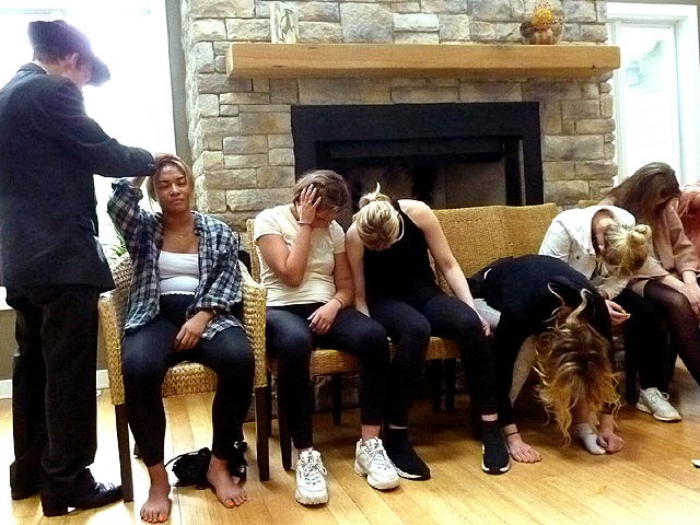 Volunteer's hand stuck to her head at Chicago area sorority hypnosis show.