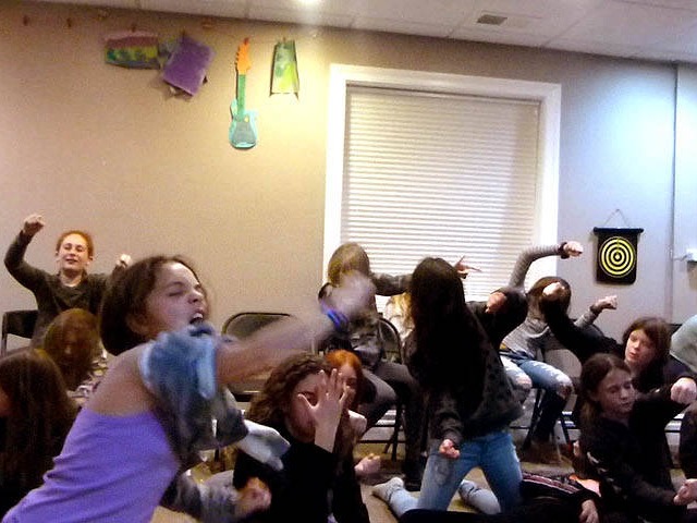 Tween girls wave their arms wildly at a Chicago area home hypnosis show.